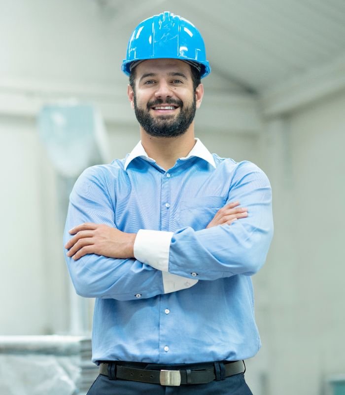 Ingeniero industrial con casco azul sonriendo en un entorno técnico en Lleida en página de Contacto con ingeniero industrial en Lleida para licencias y certificados